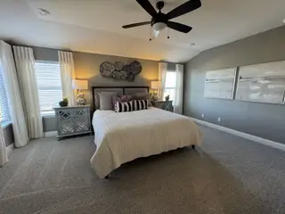 A cozy bedroom featuring a plush bed, elegant decor, soft carpet, and ample natural light.