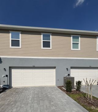 A beautifully designed townhome exterior with stone accents, elegant landscaping, and a welcoming porch in Gardenia Reserve by Mattamy Homes (Apopka, FL).