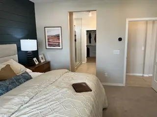 Model Home A cozy bedroom featuring a shiplap accent wall, modern decor, and a walk-in closet with a glass shower.