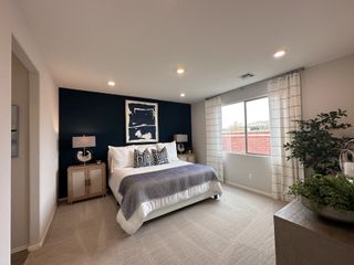 Model Home A modern bedroom with a navy accent wall, cozy bed, and natural light from a large window, creating a serene atmosphere.