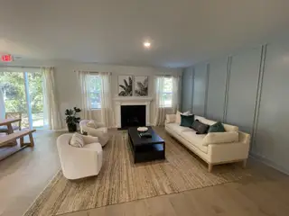 A cozy living room with soft seating, a sleek coffee table, and fireplace. Natural light and greenery add warmth.