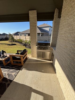 A cozy outdoor patio with a built-in grill, modern seating, and a landscaped yard perfect for entertaining.