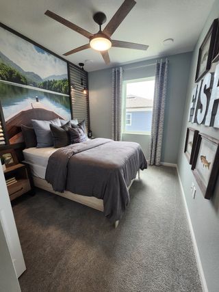 A cozy bedroom featuring a nature mural, gray bedding, and a modern ceiling fan for a tranquil retreat.