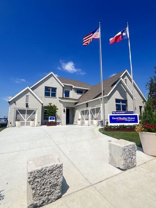 Street view A beautiful modern home with dual flags and a sleek driveway in Terraces – Classics by David Weekley Homes (Rockwall, TX).