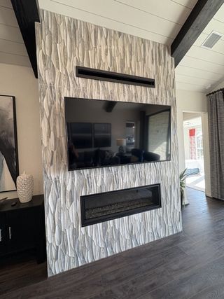 A dramatic fireplace with textured tile, built-in TV, and a sleek linear gas insert in Esperanza by Scott Felder Homes (Boerne, TX).
