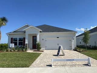 Street view A charming white home with red shutters and a manicured lawn in SilverLeaf: Silver Meadows 60s by Lennar (St. Augustine, FL).