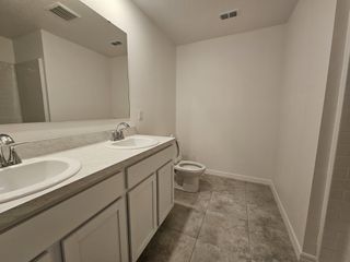 A modern bathroom features dual sinks, a large mirror, and tiled flooring for a sleek and functional design.