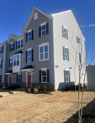 A charming gray townhouse with black shutters and red doors in Dillon Lakes by Ryan Homes (Charlotte, NC).