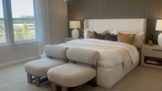 A cozy bedroom featuring an elegant upholstered bed, soft beige chairs, and stylish modern decor.