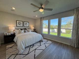 A cozy bedroom featuring a plush bed, patterned rug, and large windows offering a serene garden view.