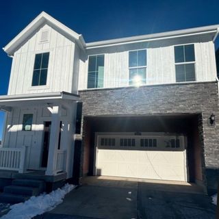 A modern two-story home with stone accents and a white exterior in Harvest Ridge: The Parkside Collection by Lennar (Aurora, CO).