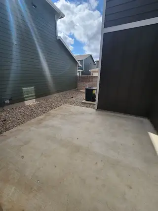 A cozy outdoor patio area with concrete flooring and privacy fence, perfect for relaxation and gatherings.