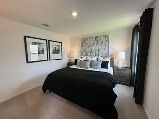 Model Home A chic bedroom featuring a plush bed with monochrome accents, elegant artwork, and soft lighting for a cozy ambiance.