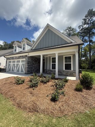 A charming gray home with stone accents and a manicured lawn in Candleberry Place by Lennar (Sharpsburg, GA).