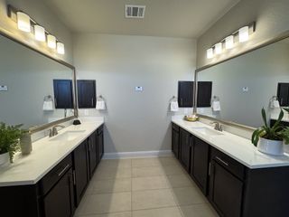 Model Home A modern bathroom with dual sinks, sleek dark cabinets, large mirrors, and elegant lighting.