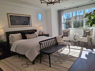 Model Home A cozy bedroom with a plush bed, elegant decor, stylish seating area, and large window bringing in natural light.