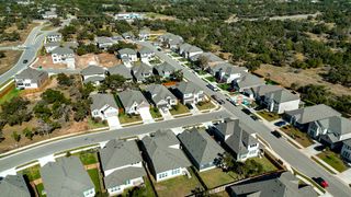 Street view Aerial view of charming homes and lush landscapes in Retreat at San Gabriel by Brightland Homes (Georgetown, TX).