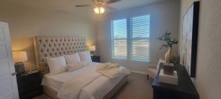Model Home A cozy bedroom with a tufted headboard, plush bedding, and large windows. Neutral tones and elegant decor create a tranquil space.