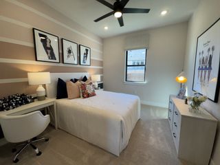 A charming bedroom with soft pink striped walls, stylish decor, and a cozy desk setup for study or work.