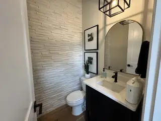 A modern powder room featuring textured walls, a sleek vanity, and elegant lighting fixtures.