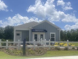A charming gray home with a quaint porch and landscaped garden in The Oaks at Center Station by D.R. Horton (Hollywood, SC).