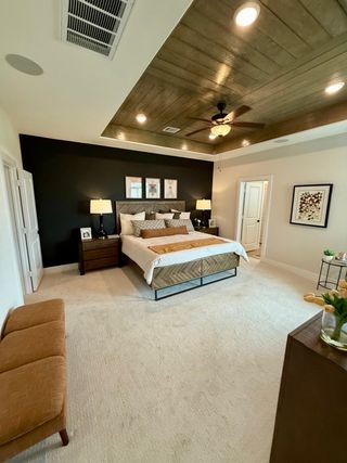 Spacious bedroom with a modern dark accent wall, wooden ceiling, cozy lighting, and elegant decor.