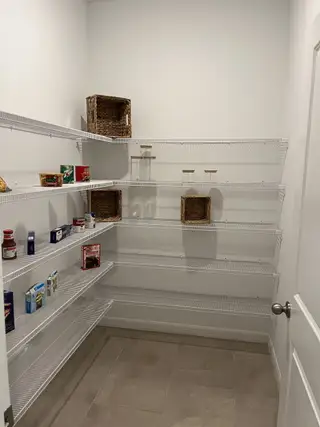 A spacious pantry with white wire shelving and tiled flooring, perfect for organized kitchen storage.