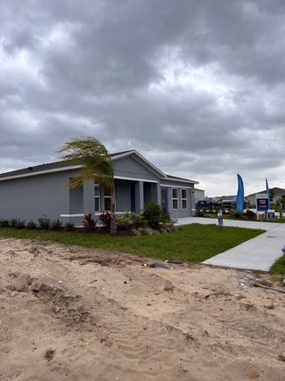 A modern gray home with neat landscaping under cloudy skies in The Reserve at Bradbury Creek by Century Complete (Haines City, FL).