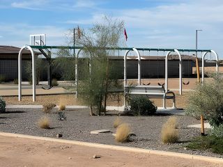 A community park with swings, a basketball hoop, and desert landscaping in The Skyview Collection at North Copper Canyon by Century Communities (Surprise, AZ).