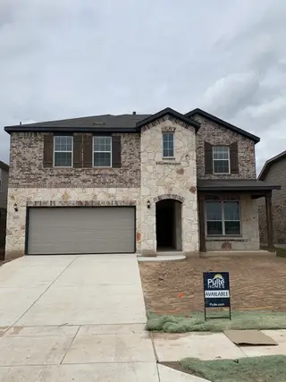A charming stone and brick home with wooden shutters in Lagos by Pulte Homes (Manor, TX).