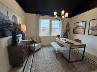 A sophisticated home office with a black ceiling, rustic wood furniture, and large windows in Veramendi by Brightland Homes (New Braunfels, TX).