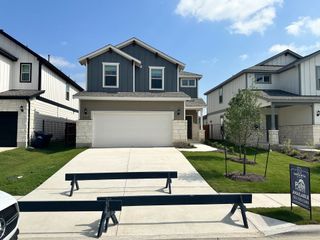 Street view A modern blue-gray home with a spacious driveway and neat lawn in Santa Rita Ranch by Pulte Homes (Liberty Hill, TX).
