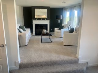 A cozy living room featuring a fireplace, white sofas, and a stylish black accent wall, illuminated by natural light.