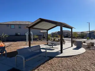 A beautiful community area with benches and a shaded structure at The Villages at North Copper Canyon by Landsea Homes (Surprise, AZ).