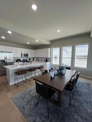 A modern kitchen and dining area with sleek cabinetry, a large island, and abundant natural light through expansive windows.