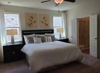 A cozy bedroom with plush bedding, natural light, and tasteful decor. Features an ensuite bathroom for added convenience.