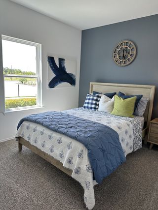 A cozy bedroom featuring a soft blue accent wall, stylish bedding, and elegant decor with a view through a large window.