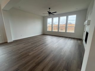 Model Home An airy living room with sleek wood flooring, large windows, and a modern ceiling fan for cozy family gatherings.