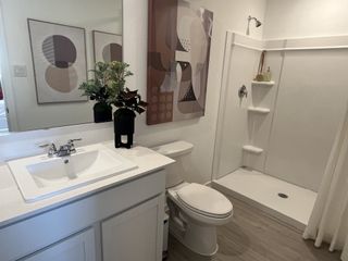 A modern bathroom with sleek vanity, large mirror, abstract art, and elegant shower design.
