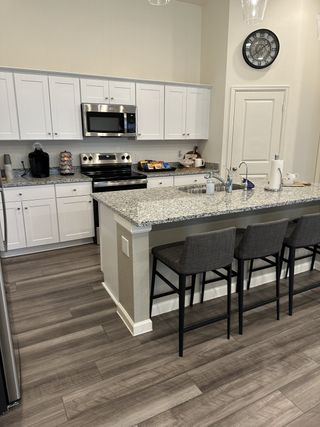 A modern kitchen with sleek granite countertops, white cabinetry, and stainless steel appliances.