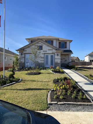 A charming stone facade home with manicured lawn in Meadow Park by First America Homes (Conroe, TX).