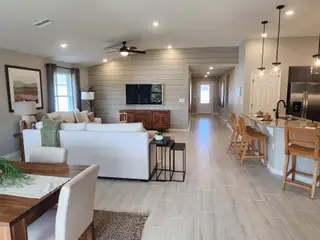 An open-concept living space with sleek tile flooring, cozy seating, and a modern kitchen with pendant lighting.