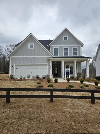Street view A charming farmhouse-style home with a covered front porch and elegant curb appeal in Hunters Creek by Pulte Homes (Flowery Branch, GA).