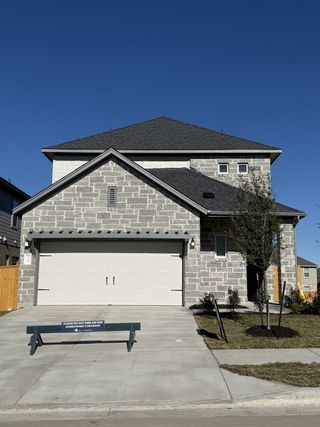 Street view A modern gray brick home with a spacious driveway in Cedar Brook by M/I Homes (Leander, TX).