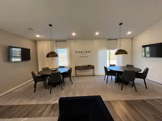 A modern meeting room featuring round tables, sleek chairs, and pendant lighting, creating a contemporary, inviting ambiance.