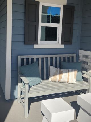 Model Home A charming front porch with blue siding, a cozy bench, and decorative shutters in Amelia National by ICI Homes (Fernandina Beach, FL).