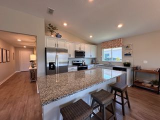 A spacious kitchen with granite countertops, white cabinetry, and stainless steel appliances.