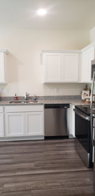 Model Home A modern kitchen with sleek white cabinets, granite countertops, and stainless steel appliances.