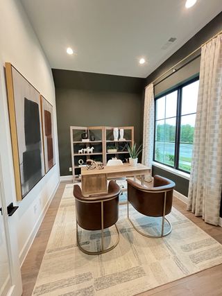 A stylish home office with leather chairs, abstract art, and large windows allowing natural light to fill the space.
