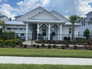 A charming white residence with lush landscaping in Reflections at Nocatee by Providence Homes (Nocatee, FL).